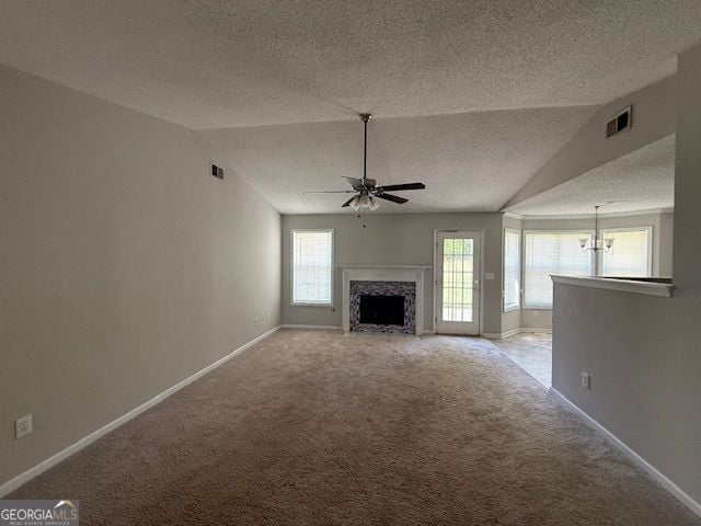 unfurnished living room with ceiling fan with notable chandelier, carpet flooring, lofted ceiling, and visible vents