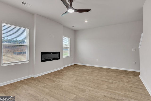 219 Rusty Plow Ln Unit 69, Perry, GA 31069 - unfurnished living room featuring a glass covered fireplace, light wood-type flooring, baseboards, visible vents, and ceiling fan