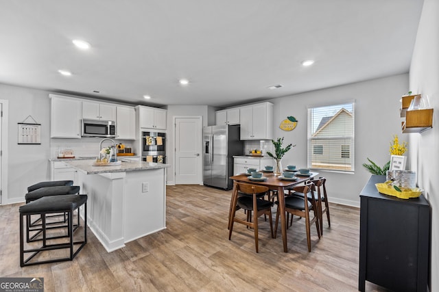 219 Rusty Plow Ln Unit 69, Perry, GA 31069 - kitchen with stainless steel appliances, light wood finished floors, white cabinetry, and decorative backsplash