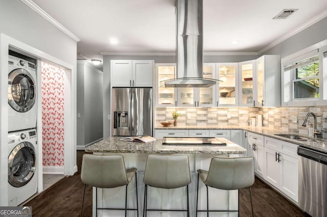 kitchen with visible vents, a sink, ornamental molding, appliances with stainless steel finishes, and stacked washing maching and dryer