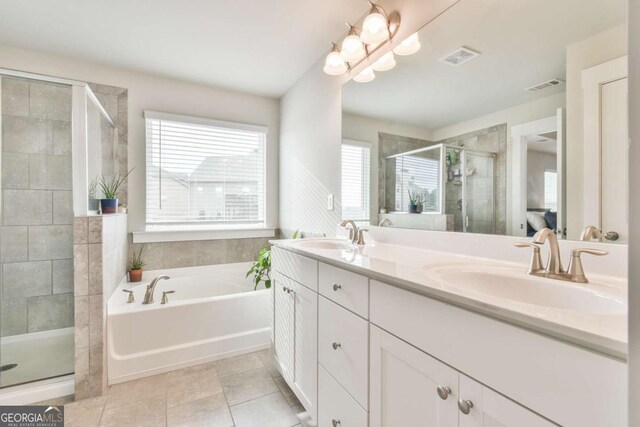 bathroom with a stall shower, double vanity, a sink, and visible vents