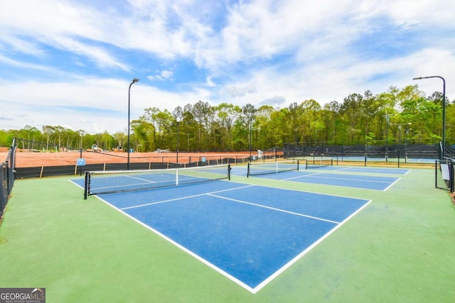 view of tennis court with community basketball court and fence