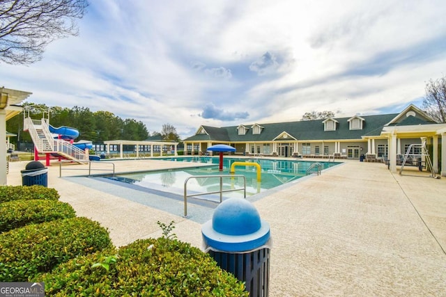pool featuring a patio area, a water play area, and a water slide
