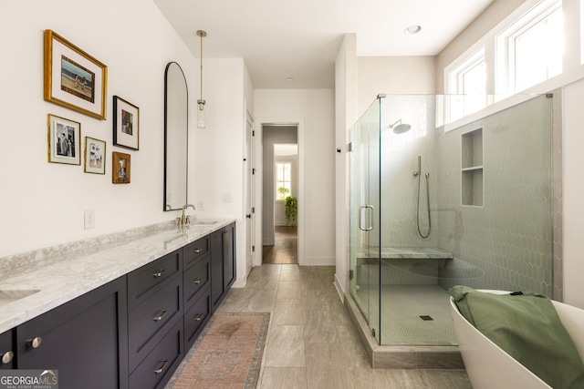 bathroom with a sink, a wealth of natural light, a shower stall, and double vanity