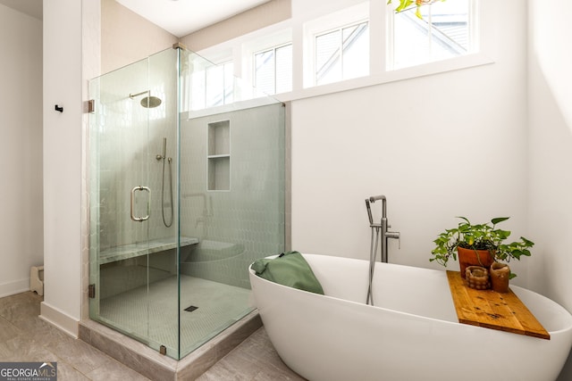 full bathroom with a shower stall, a freestanding bath, and baseboards