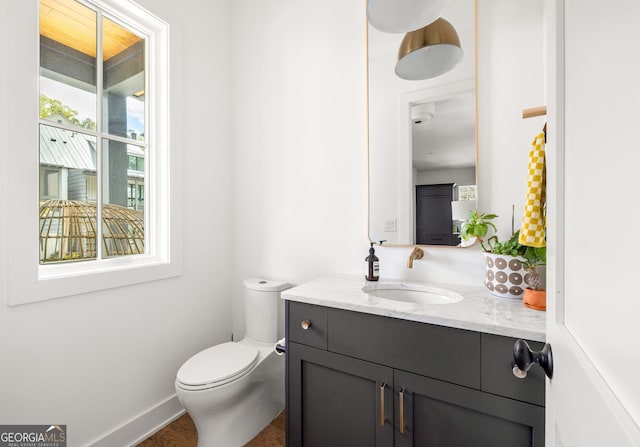 bathroom with toilet, vanity, and baseboards
