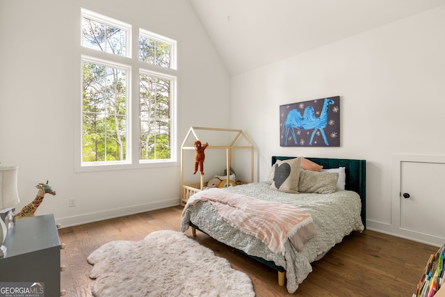 bedroom with high vaulted ceiling, multiple windows, baseboards, and wood finished floors