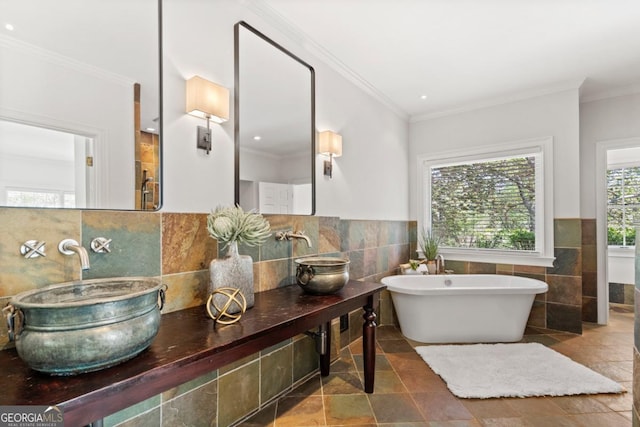 full bathroom featuring a freestanding bath, tile walls, a sink, and crown molding