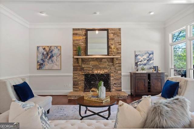 living area with ornamental molding, a stone fireplace, and wood finished floors