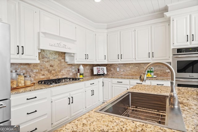 kitchen featuring appliances with stainless steel finishes, custom range hood, a sink, and white cabinetry