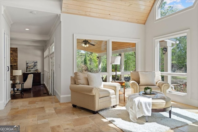 sitting room featuring baseboards, ornamental molding, stone tile flooring, and a wealth of natural light