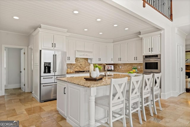 kitchen featuring tasteful backsplash, custom range hood, stone tile flooring, and stainless steel appliances