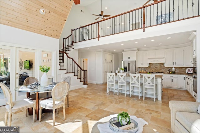 dining space with ceiling fan, stairway, recessed lighting, high vaulted ceiling, and stone finish flooring