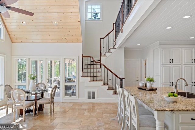 dining room with visible vents, stone finish floor, plenty of natural light, and stairs