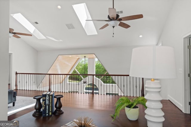 interior space featuring vaulted ceiling with skylight, ceiling fan, visible vents, recessed lighting, and wood finished floors