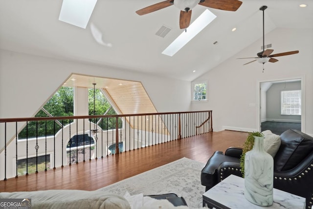 living area featuring visible vents, ceiling fan, lofted ceiling with skylight, and wood finished floors