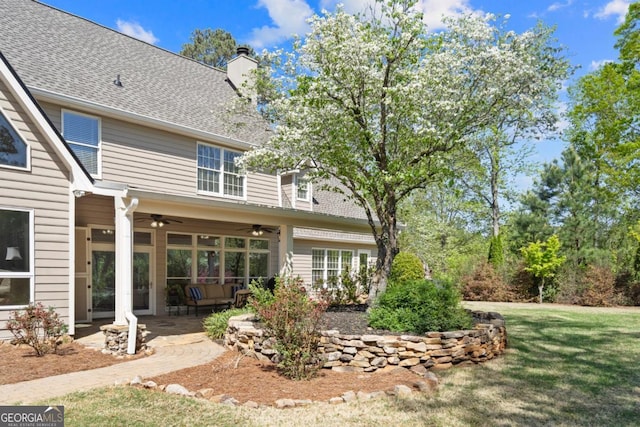 back of house with a patio, a chimney, a ceiling fan, and a lawn