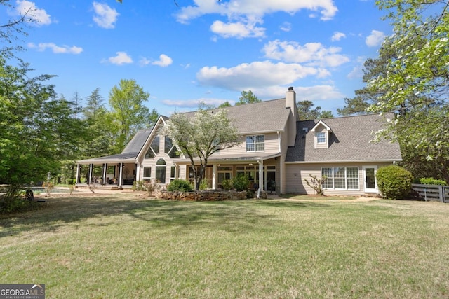 back of house featuring fence, a shingled roof, a chimney, and a lawn