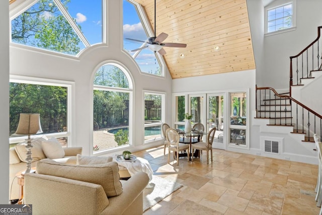 sunroom / solarium featuring visible vents, plenty of natural light, a high ceiling, and stone tile flooring