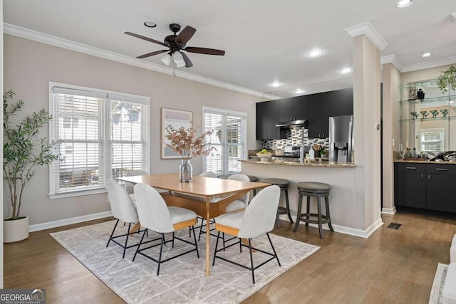 dining space featuring crown molding, ceiling fan, wood finished floors, and baseboards
