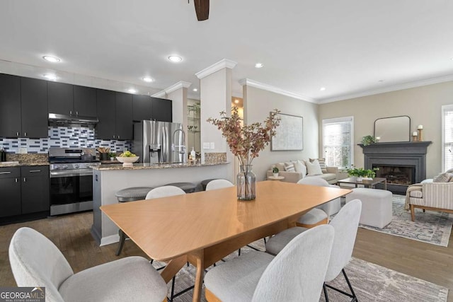 dining area featuring ornamental molding, a fireplace, dark wood finished floors, and recessed lighting