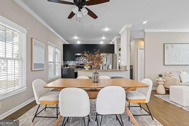 dining space featuring ceiling fan, baseboards, ornamental molding, and wood finished floors