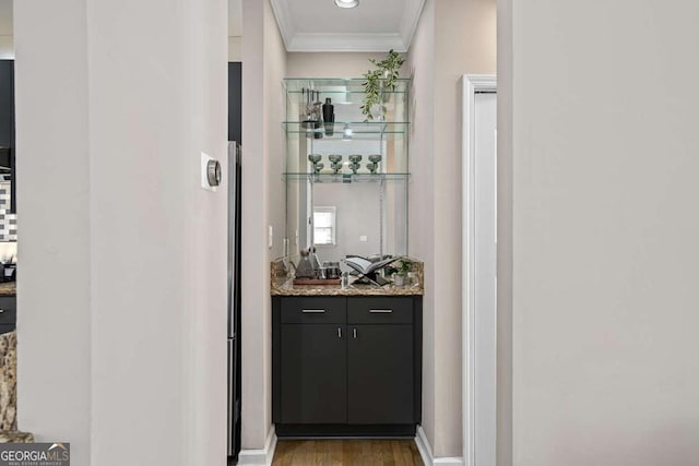 bar with ornamental molding, wood finished floors, and indoor wet bar