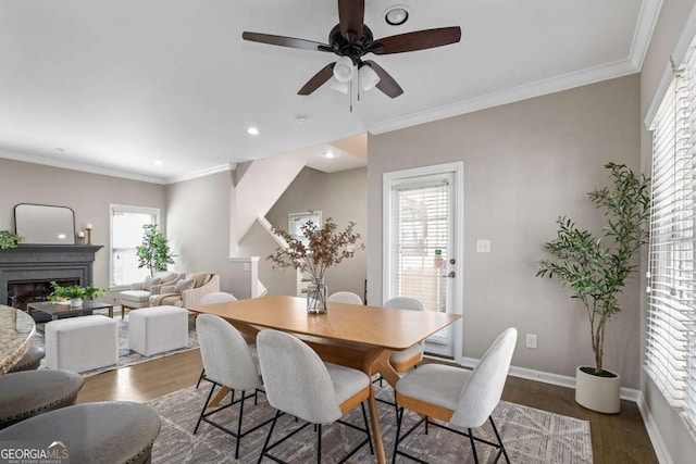 dining room with crown molding, wood finished floors, ceiling fan, and a fireplace