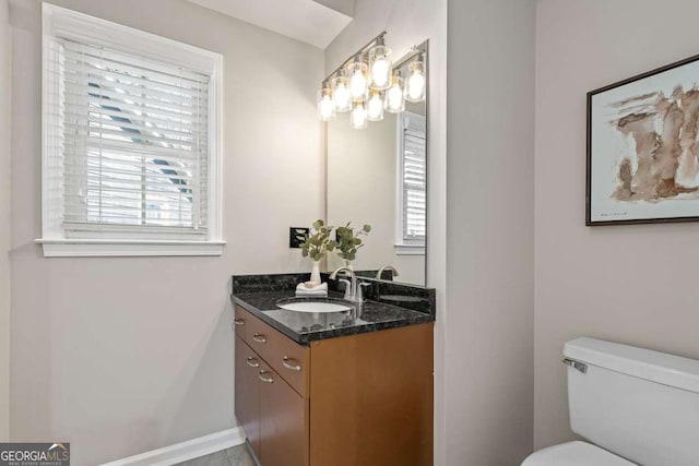 bathroom featuring toilet, vanity, and a wealth of natural light