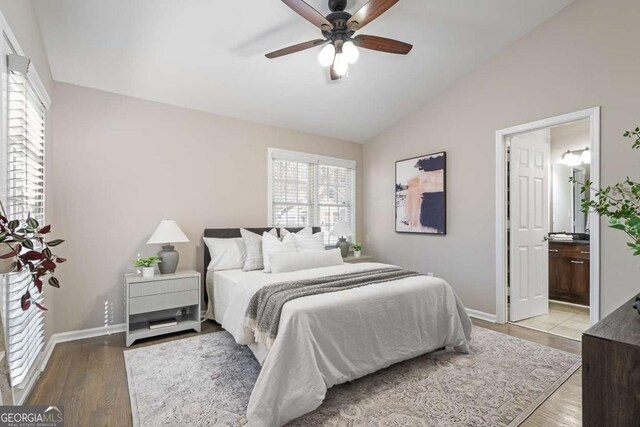 bedroom with ceiling fan, ensuite bathroom, light wood-type flooring, lofted ceiling, and baseboards