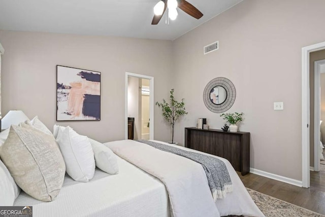 bedroom featuring visible vents, baseboards, ensuite bathroom, wood finished floors, and lofted ceiling