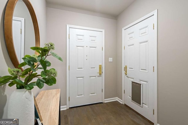 foyer with dark wood-style flooring and baseboards