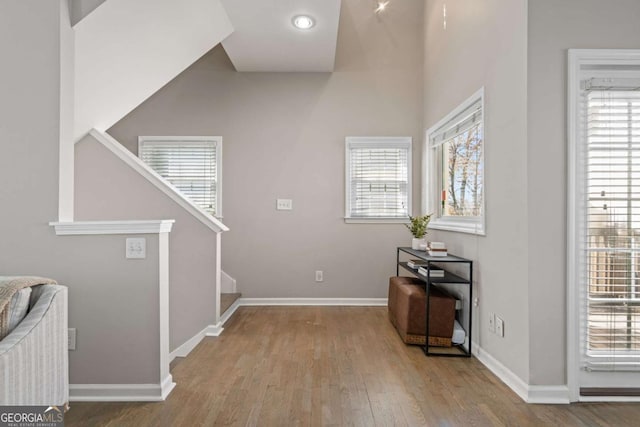 foyer entrance with baseboards, stairway, plenty of natural light, and wood finished floors