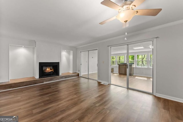 6500 Gaines Ferry Rd, Flowery Branch, GA 30542 - unfurnished living room with baseboards, a warm lit fireplace, ceiling fan, crown molding, and wood finished floors