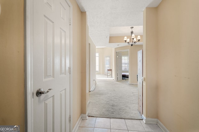 1250 Parkwood Cir SE Unit 2310, Atlanta, GA 30339 - corridor with light tile patterned floors, baseboards, a notable chandelier, a textured ceiling, and light colored carpet