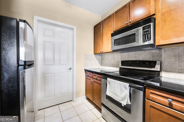 1250 Parkwood Cir SE Unit 2310, Atlanta, GA 30339 - kitchen with brown cabinetry, light tile patterned flooring, backsplash, and appliances with stainless steel finishes