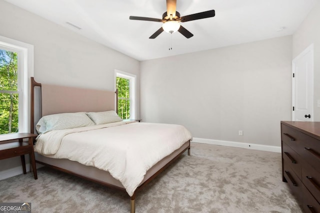 bedroom featuring visible vents, baseboards, a ceiling fan, and light carpet