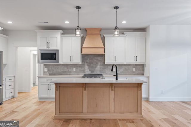kitchen with custom exhaust hood, a sink, light countertops, stove, and built in microwave