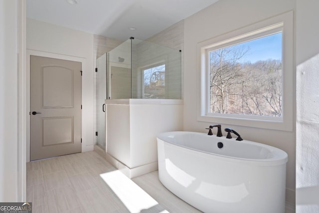 full bathroom with a shower stall and a freestanding bath