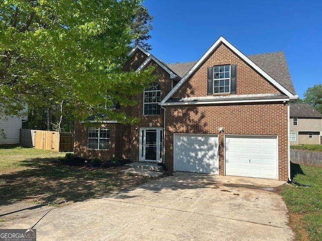 traditional-style house with driveway, fence, an attached garage, and brick siding