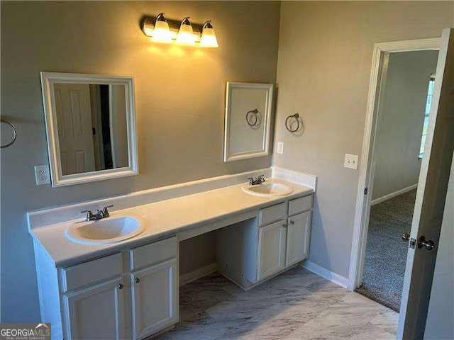 full bath with marble finish floor, double vanity, and a sink