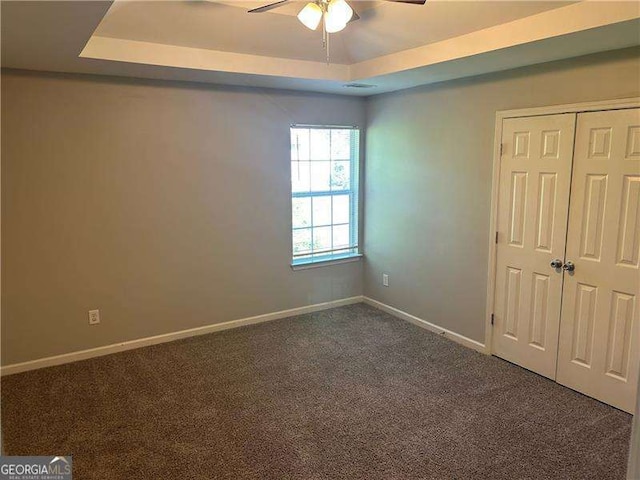 unfurnished bedroom with baseboards, a closet, carpet flooring, and a tray ceiling
