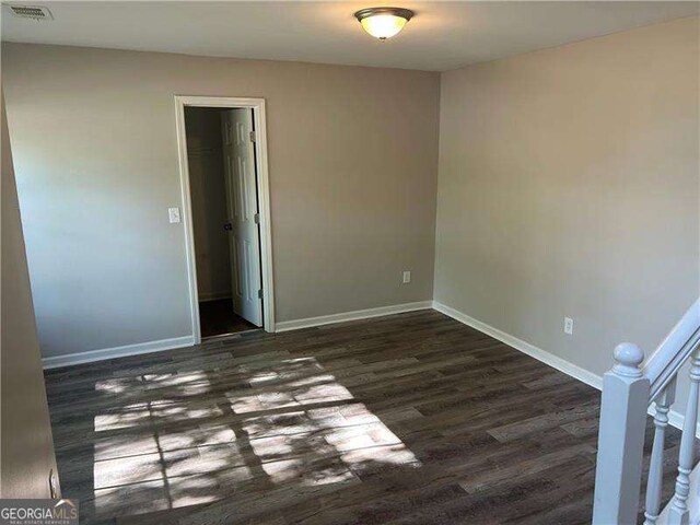 spare room with visible vents, dark wood-style floors, and baseboards