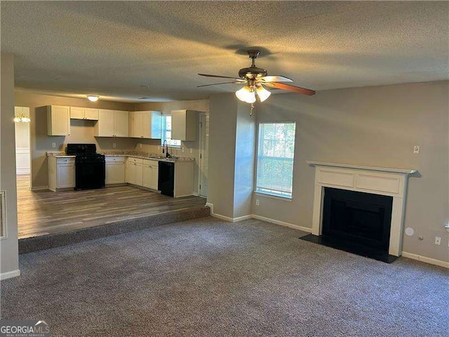 kitchen with dark colored carpet, black appliances, a ceiling fan, and a sink