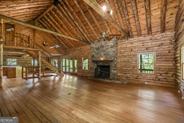 unfurnished living room with a healthy amount of sunlight, wood-type flooring, a ceiling fan, and a stone fireplace