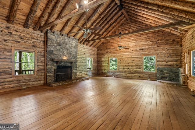 unfurnished living room with beam ceiling, a stone fireplace, and hardwood / wood-style flooring