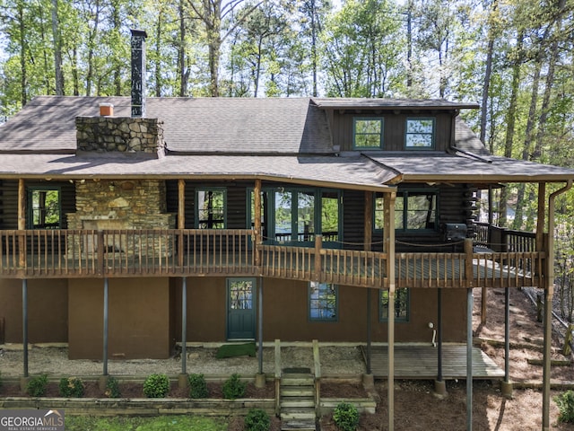 back of house with roof with shingles, log siding, and a wooden deck