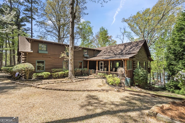 log-style house with a shingled roof, board and batten siding, covered porch, and log exterior