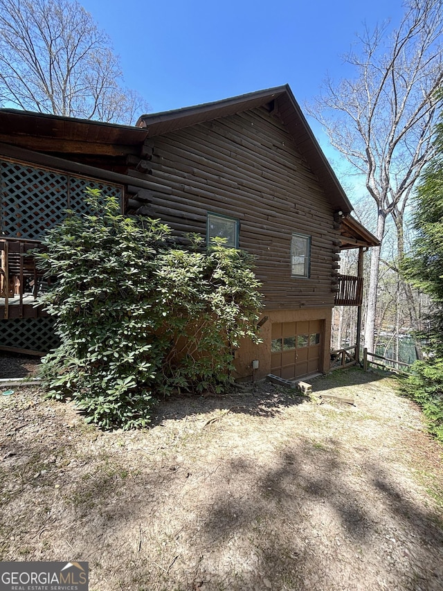 view of side of home with an attached garage, log siding, and driveway