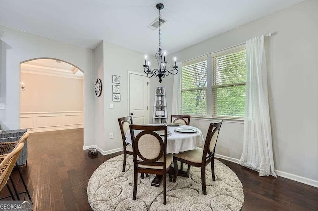 dining room with a decorative wall, an inviting chandelier, dark wood finished floors, arched walkways, and visible vents